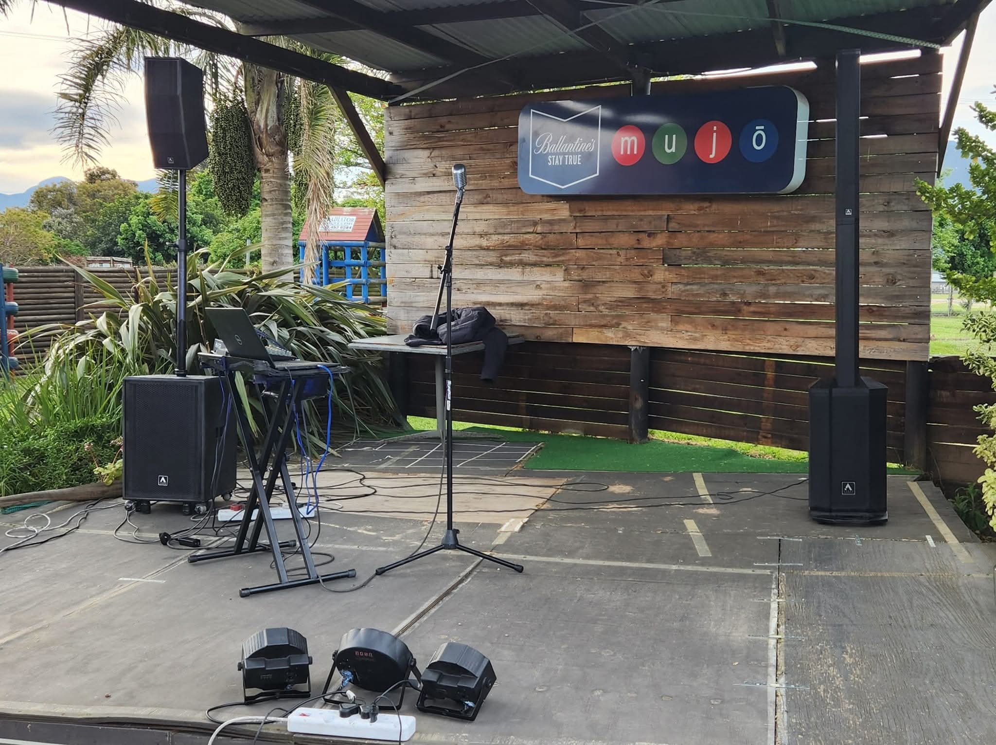 Outdoor stage with speaker columns, microphone, and wooden backdrop